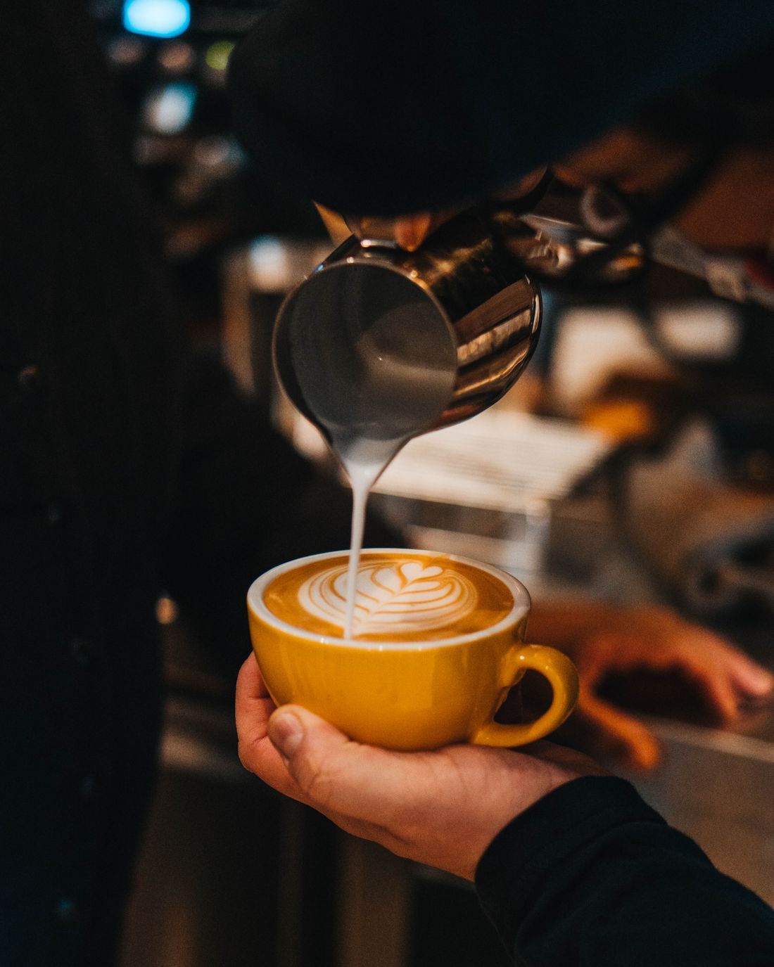Barista heller melk i en kopp med latte art